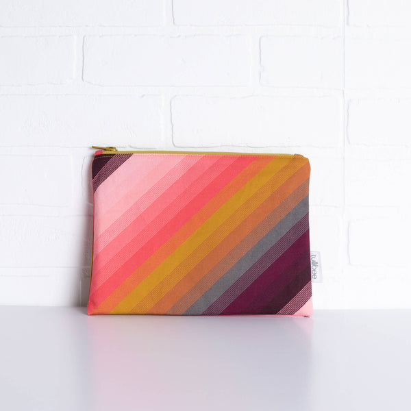 tullibee agnes tonal diagonal stripe midi rectangular pouch propped against a white brick wall (front view)