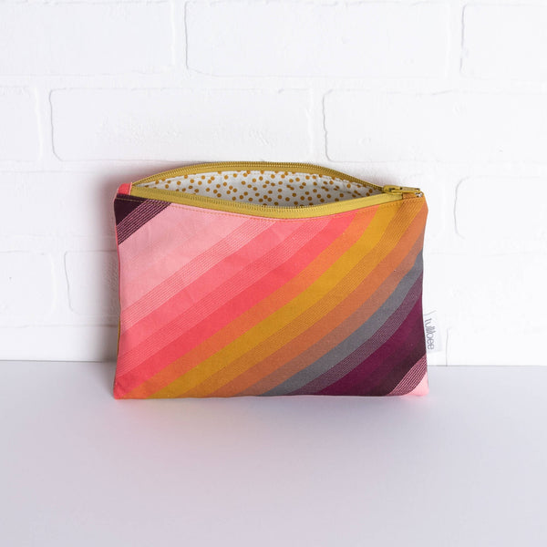 tullibee agnes tonal diagonal stripe midi rectangular pouch propped against a white brick wall with zip top open & view of mustard spot lining