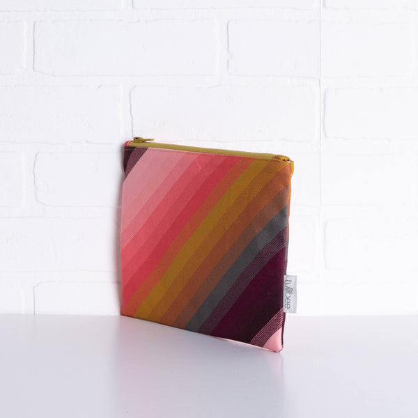 tullibee agnes tonal diagonal stripe midi rectangular pouch propped upright against a white brick wall at an angle to show the depth of the pouch