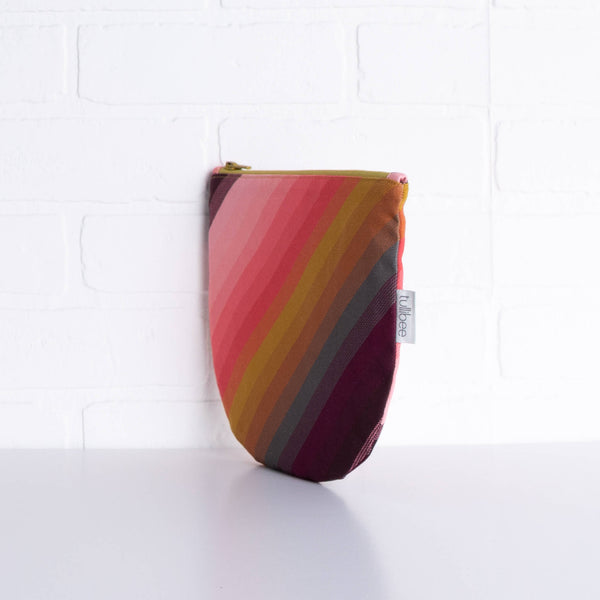 tullibee agnes tonal diagonal stripe midi round pouch propped upright against a white brick wall at an angle to show the depth of the pouch