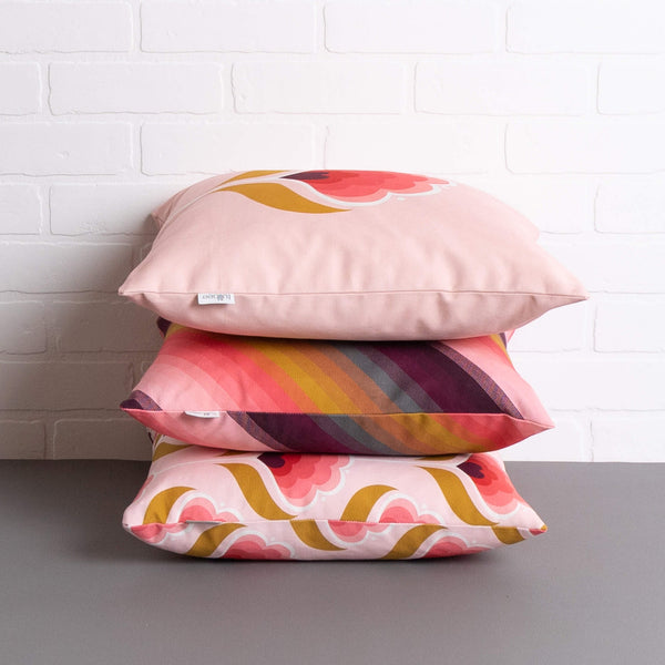 tullibee margot in the middle large retro floral cushion, agnes cushion & margot all over print cushion stacked on top one another on a concrete floor in front of a white brick wall