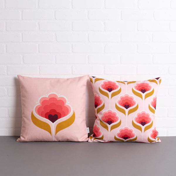tullibee margot in the middle large retro floral cushion & margot all over print cushion sat side by side on a concrete floor in front of a white brick wall