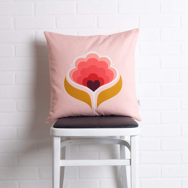 tullibee margot in the middle large retro floral cushion, in cherry flamingo & mustard colours sat on a stool in front of a white brick wall