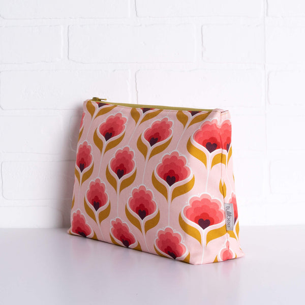tullibee mini margot retro floral maxi pouch in front of a white brick wall at an angle to show the depth of the pouch & gusset