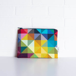 tullibee jules rainbow geometric triangle midi rectangular pouch propped against a white brick wall (front view)