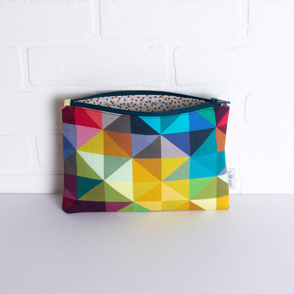 tullibee jules rainbow geometric triangle midi rectangular pouch propped against a white brick wall with zip top open & view of mustard spot lining