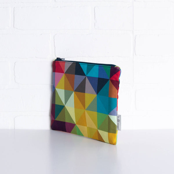 tullibee jules rainbow geometric triangle midi rectangular pouch propped upright against a white brick wall at an angle to show the depth of the pouch