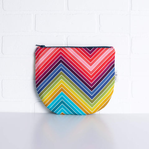 tullibee marni rainbow zig-zag midi round pouch propped against a white brick wall (front view)
