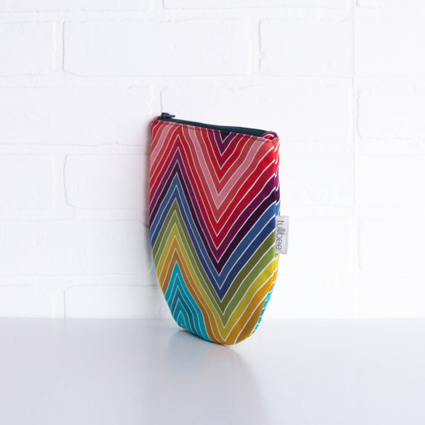 tullibee marni rainbow zig-zag midi round pouch propped upright against a white brick wall at an angle to show the depth of the pouch