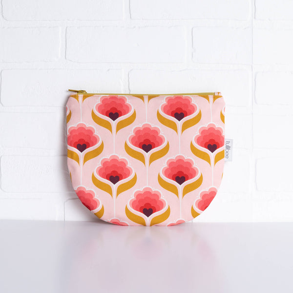 tullibee mini margot retro floral midi round pouch propped against a white brick wall (front view)